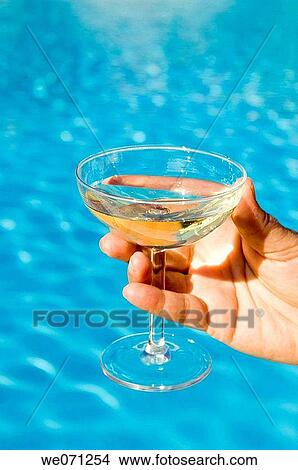 Hand holding champagne glass in front of pool. View Large Photo Image Picture - Hand holding champagne glass in front of pool.. Fotosearch
