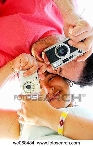 Man and woman holding cameras. View Large Photo Image Picture - Man and woman holding cameras.. Fotosearch