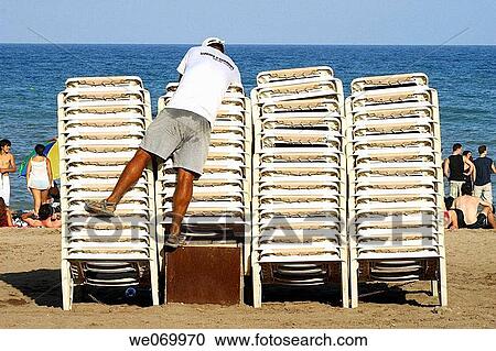 Man stacking beach chairs, Barceloneta beach, Barcelona. Catalonia, Spain View Large Photo Image Stock Image - Man stacking beach chairs, Barceloneta beach, Barcelona. Catalonia, Spain. Fotosearch