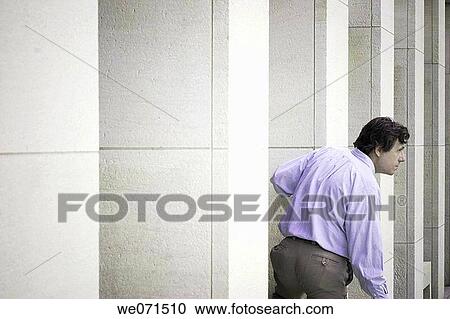 Stock Image - Man standing between the concrete structures in front of a building. Fotosearch