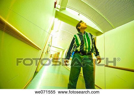 Stock Photography - Man standing in an office building hallway. Fotosearch