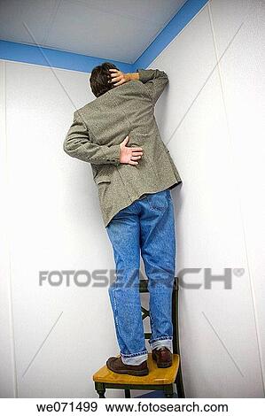 Man standing on a chair, facing the wall View Large Photo Image Stock Photo - Man standing on a chair, facing the wall. Fotosearch