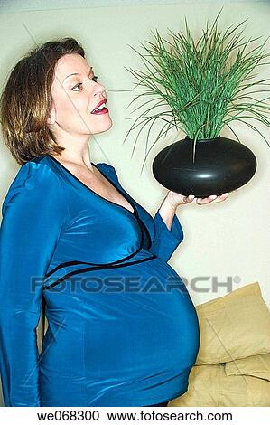 Pregnant woman holding a plant in her hand View Large Photo Image Stock Image - Pregnant woman holding a plant in her hand. Fotosearch