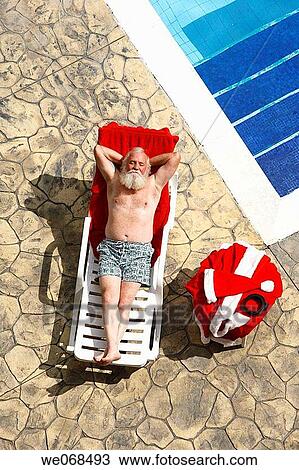 Santa relaxes on the side of a swimming pool View Large Photo Image Stock Image - Santa relaxes on the side of a swimming pool. Fotosearch