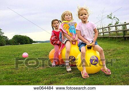 three girls on bouncy hoppers in a field laughing View Large Photo Image Picture - three girls on bouncy hoppers in a field laughing. Fotosearch