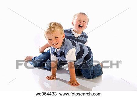 Stock Image - two brothers aged 5 and 3 playing together on the floor of the studio. Fotosearch