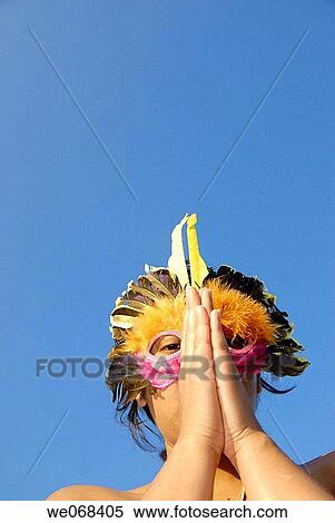 Woman wearing a colored mask resembling a bird. Hands joined as if worshiping-praying View Large Photo Image Stock Photography - Woman wearing a colored mask resembling a bird. Hands joined as if worshiping-praying. Fotosearch