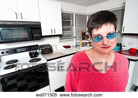 Stock Photography - Woman, wearing sunglasses, posing in her kitchen. Fotosearch