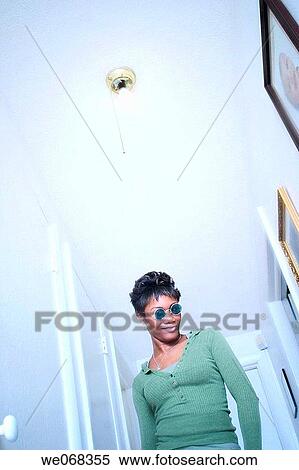 Young black woman, wearing sunglasses, standing underneath a light fixture View Large Photo Image Stock Photography - Young black woman, wearing sunglasses, standing underneath a light fixture. Fotosearch