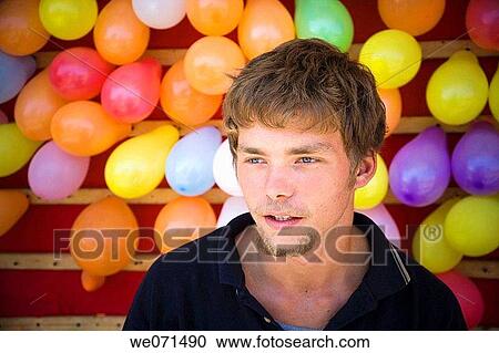 Young male carnival worker standing in front of his balloon-popping game View Large Photo Image Stock Image - Young male carnival worker standing in front of his balloon-popping game. Fotosearch