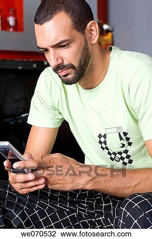 Young man using cell phone View Large Photo Image Stock Image - Young man using cell phone. Fotosearch