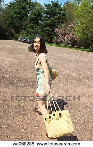 Young woman, carrying a bag and a pillow, walking in a parking lot View Large Photo Image Stock Photo - Young woman, carrying a bag and a pillow, walking in a parking lot. Fotosearch