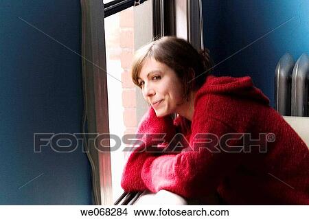 Young woman sitting next to a window View Large Photo Image Picture - Young woman sitting next to a window. Fotosearch