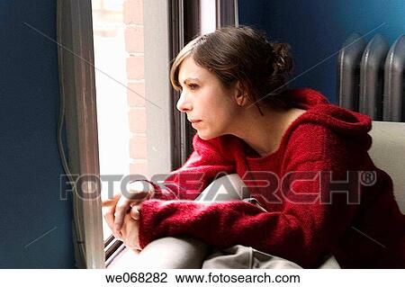 Young woman sitting next to a window View Large Photo Image Stock Image - Young woman sitting next to a window. Fotosearch