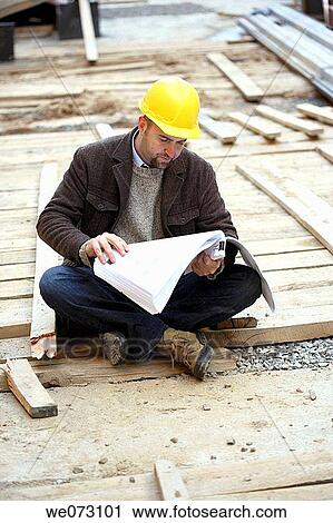 Architect, Engineer, General Contractor sitting on the ground reading plans View Large Photo Image Stock Image - Architect, Engineer, General Contractor sitting on the ground reading plans. Fotosearch