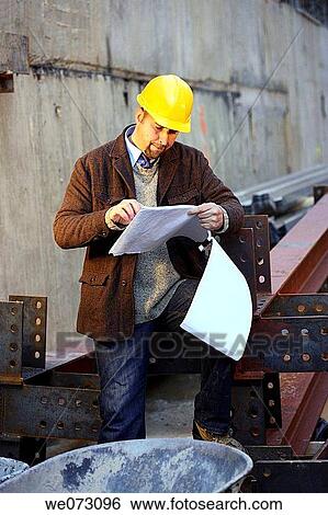 Architect, Engineer, General Contractor with hard hat on construction site reading plans View Large Photo Image Stock Photograph - Architect, Engineer, General Contractor with hard hat on construction site reading plans. Fotosearch