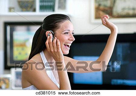 Stock Photography - at-home, cell phone, brunette, Arms raised. Fotosearch
