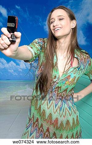 Picture - beach, brunette, camera, cell phone. Fotosearch