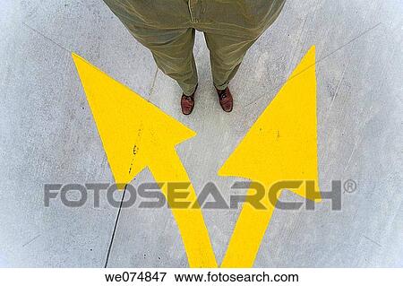 Close-up of a man's legs and feet standing next to yellow traffic arrows painted on the street. View Large Photo Image Stock Photo - Close-up of a man's legs and feet standing next to yellow traffic arrows painted on the street.. Fotosearch