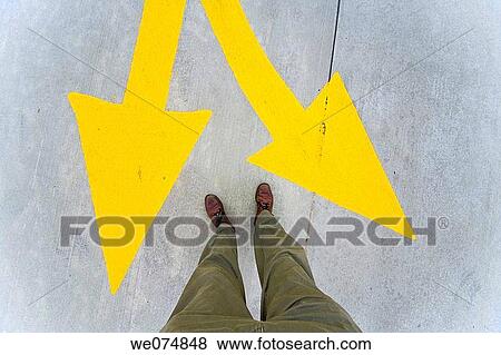 Close-up of a man's legs and feet standing next to yellow traffic arrows painted on the street. View Large Photo Image Stock Photo - Close-up of a man's legs and feet standing next to yellow traffic arrows painted on the street.. Fotosearch