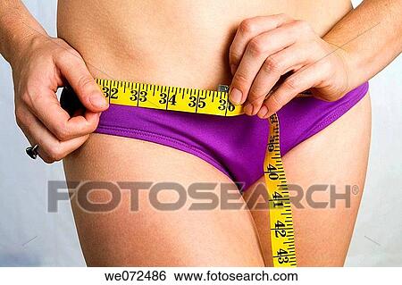 Closeup of young woman in purple bikini measuring her hips. In studio. View Large Photo Image Stock Photograph - Closeup of young woman in purple bikini measuring her hips. In studio.. Fotosearch