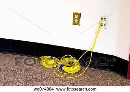 Coil of yellow cable, with one end attached to a wall jack, sitting on the floor in the hallway of an office building. View Large Photo Image Picture - Coil of yellow cable, with one end attached to a wall jack, sitting on the floor in the hallway of an office building.. Fotosearch