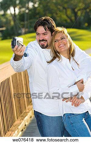 Couple taping themselves with camcorder in the park, Deerfiled Beach, Florida, USA View Large Photo Image Stock Photo - Couple taping themselves with camcorder in the park, Deerfiled Beach, Florida, USA. Fotosearch