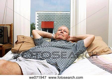 Elderly man rests comfortably on bed by window. View Large Photo Image Stock Photo - Elderly man rests comfortably on bed by window.. Fotosearch