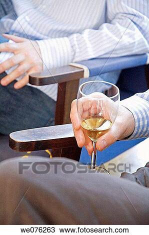 Stock Image - Friends at a winetasting, holding white wine. Fotosearch