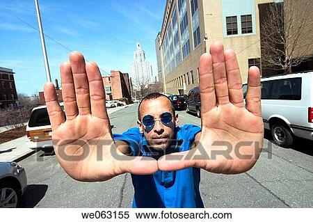 Stock Photography - Hispanic man, wearing blue sunglasses, posing on a city street. Fotosearch