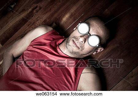 Hispanic man wearing funny round glasses while lying on a wood floor View Large Photo Image Picture - Hispanic man wearing funny round glasses while lying on a wood floor. Fotosearch