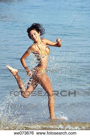 Stock Photograph - Latin girl playing on the beach. Fotosearch