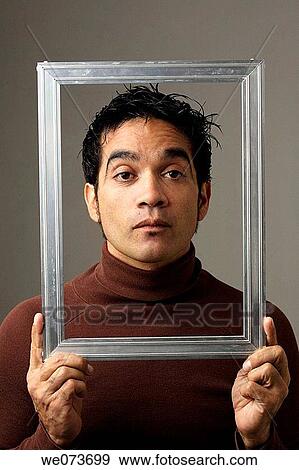Latin man poses behind a picture frame View Large Photo Image Stock Photo - Latin man poses behind a picture frame. Fotosearch