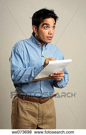 Latin man writes down on a pad View Large Photo Image Stock Photo - Latin man writes down on a pad. Fotosearch