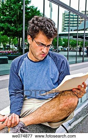 Male college student, wearing glasses, sitting outside next to a city building, studying his notes. View Large Photo Image Stock Photo - Male college student, wearing glasses, sitting outside next to a city building, studying his notes.. Fotosearch