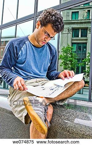 Male college student, wearing glasses, sitting outside next to a city building, studying his notes. View Large Photo Image Stock Photography - Male college student, wearing glasses, sitting outside next to a city building, studying his notes.. Fotosearch