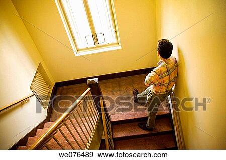 Stock Photo - Man on a stair in an office building stairwell.. Fotosearch