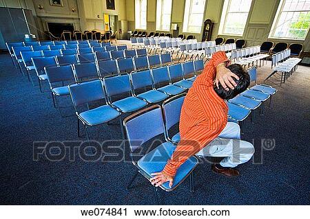 Man sitting on a chair in an otherwise empty auditorium. View Large Photo Image Stock Image - Man sitting on a chair in an otherwise empty auditorium.. Fotosearch