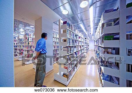 Man standing near bookshelves in a library. View Large Photo Image Stock Photograph - Man standing near bookshelves in a library.. Fotosearch