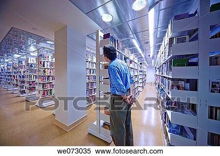 Man standing near bookshelves in a library. View Large Photo Image Stock Photography - Man standing near bookshelves in a library.. Fotosearch