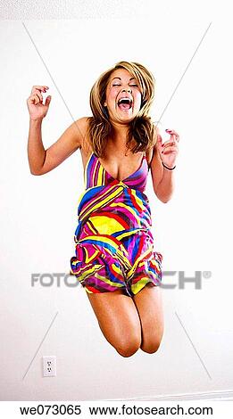 Mid 20's caucasian woman in crazy color dress jumps for joy View Large Photo Image Stock Photography - Mid 20's caucasian woman in crazy color dress jumps for joy. Fotosearch