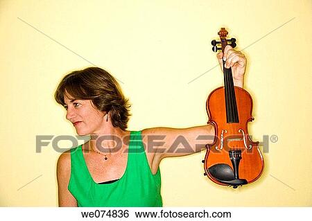 Stock Photograph - Middle age woman holding up her violin.. Fotosearch