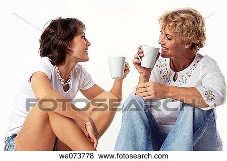 Stock Photo - Mother and daughter drink coffee and talk in a studio setting. Fotosearch