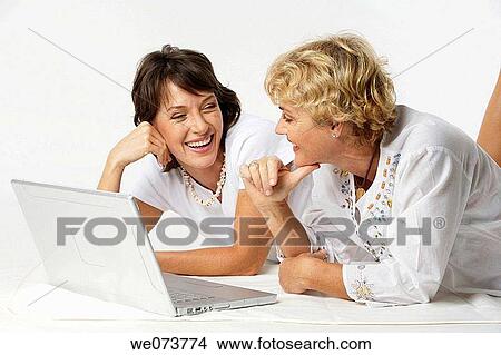 Mother and daughter interact with a notebook computer in a studio setting View Large Photo Image Picture - Mother and daughter interact with a notebook computer in a studio setting. Fotosearch