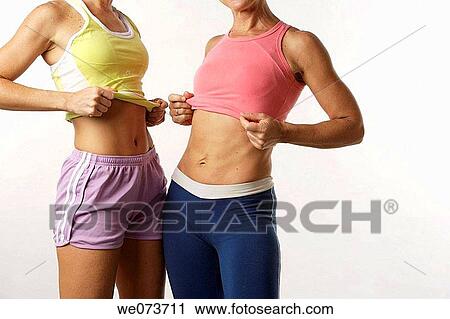 Stock Image - Mother and daughter show their flat stomachs. Fotosearch