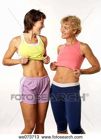 Stock Image - Mother and daughter show their flat stomachs. Fotosearch