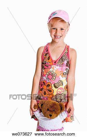 Stock Photo - Portrait of a blond girl with a cap and her toy bear. Fotosearch