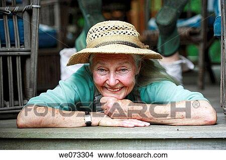 Senior woman with straw hat laying on stomach looking into camera smiling View Large Photo Image Picture - Senior woman with straw hat laying on stomach looking into camera smiling. Fotosearch