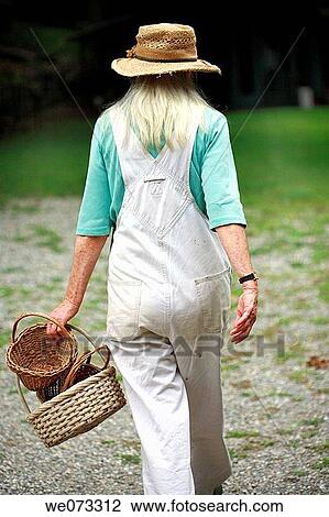Senior woman with straw hat walking with baskets in hand from back View Large Photo Image Stock Image - Senior woman with straw hat walking with baskets in hand from back. Fotosearch