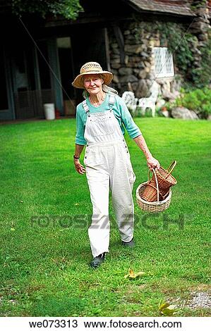 Senior woman with straw hat walking towards camera with baskets in hand View Large Photo Image Stock Image - Senior woman with straw hat walking towards camera with baskets in hand. Fotosearch